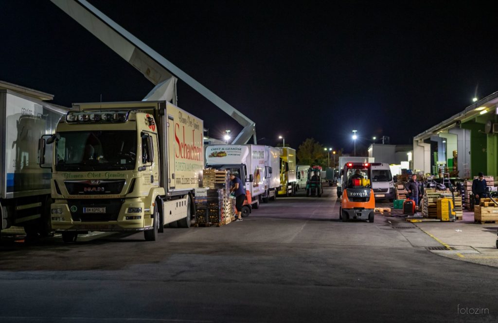 mehrere LKW beim Be- und Entladen von Kisten in der Nacht